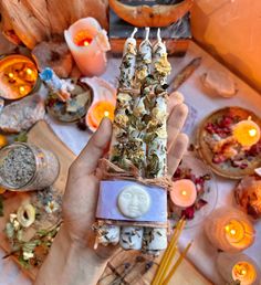 a person holding up some kind of item in front of candles and other items on the table