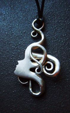 a silver pendant on a black cord with a woman's face in the center