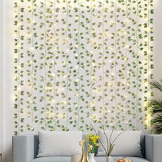 a living room with white walls and green leaves on the wall