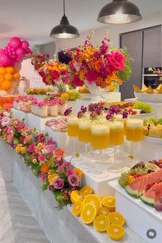 an assortment of fruits and flowers on display at a buffet table with white linens