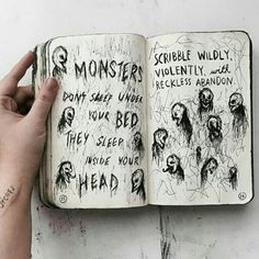 a hand holding an open book with writing on it and monsters drawn on the pages