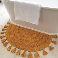 a bath tub sitting next to a rug with tassels on it