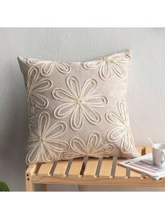 a white pillow sitting on top of a wooden bench next to a cup and book