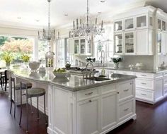 a large kitchen with white cabinets and an island in front of the stove top oven