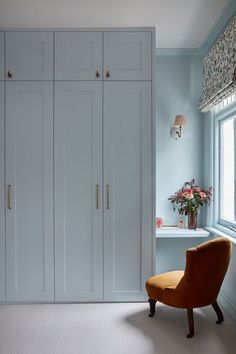 an orange chair sitting in front of a white closet with blue walls and carpeted flooring