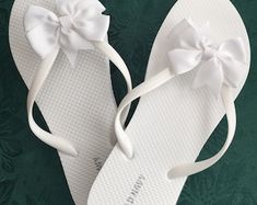 a pair of white flip flops with bows on them