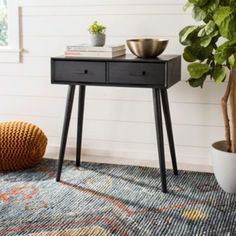 a black table with two drawers and a potted plant next to it on a rug