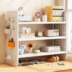 a white shelf with various items on it in a room next to a window and bookshelf