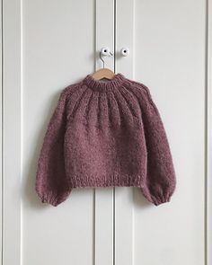 a pink sweater hanging on a white door