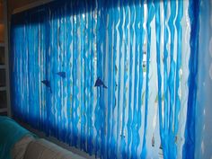 blue curtains are hanging on the wall in front of a window with fish and bubbles