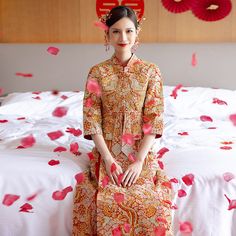 a woman sitting on top of a bed covered in petals