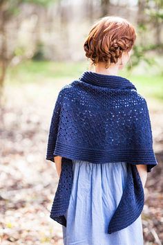 a woman standing in the woods wearing a blue shawl