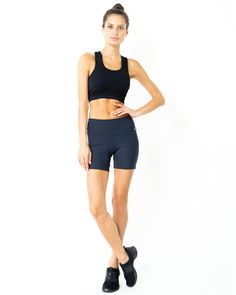 a woman in black sports bra top and shorts posing for the camera with her hands on her hips