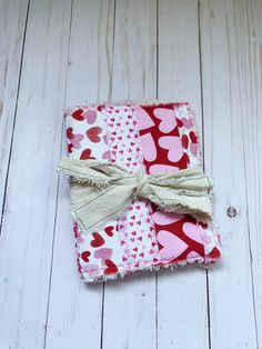 a red and pink square with hearts on it sitting on a white wooden floor next to a button