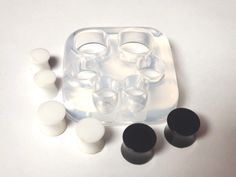 an ice tray with six cups and four eggs in it, surrounded by other plastic objects