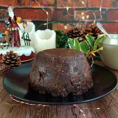 a chocolate cake sitting on top of a black plate next to christmas decorations and candles