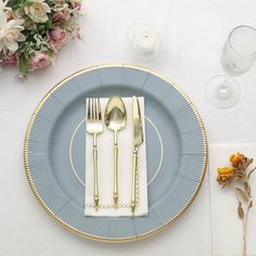 a blue plate topped with silverware next to a white and gold place setting on top of a table