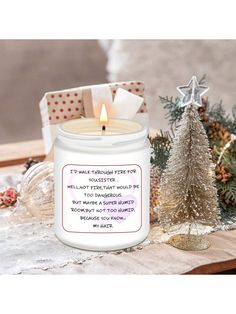 a white candle sitting on top of a table next to a christmas tree and presents