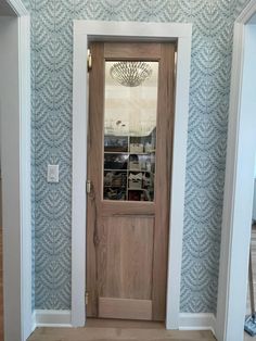 an empty room with a wooden door and blue wallpaper