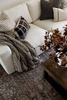 a white couch sitting next to a wooden table on top of a carpeted floor