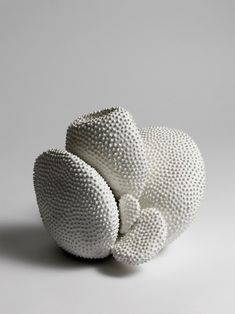 a white sculpture made out of balls on a gray surface with one ball in the middle