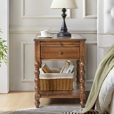 a small wooden table with a basket underneath it and a lamp on top of it