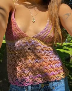 a close up of a person wearing a tank top and jeans in the grass with her hand on her hip