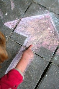 a child is drawing on the sidewalk with chalk