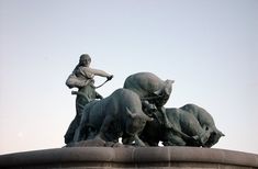 a statue of a man riding on the back of a bull with two bulls in front of him