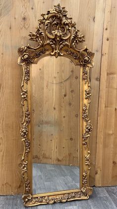 an ornate gold mirror sitting on top of a wooden floor in front of a wall