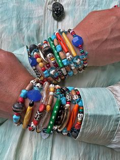 a person wearing several bracelets on their hands and holding something in the other hand