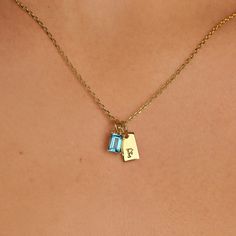 The Tiny Tag Initial Birthstone Necklace artfully combines personalized charm with a touch of color. This refined piece features a sleek gold tag, delicately engraved with your chosen initial, alongside a vibrant birthstone that dangles with light-catching allure. Perfect for celebrating a loved one's special month or adding a meaningful touch to your ensemble, this necklace serves as a daily reminder of personal significance and style. Birthstone dimension: 4 mm x 6 mm; Initial dimension: 10 mm Yellow Gold Initial Pendant Charm Necklace With Birthstone, Yellow Gold Charm Necklace With Birthstone Initial Pendant, Yellow Gold Birthstone Initial Pendant Charm Necklace, Elegant Initial Pendant Charms, Dainty Gold Birthstone Necklace With Initials, Mother's Day Birthstone Charms For Gifts, Mother's Day Gift Charms With Birthstone, Mother's Day Birthstone Charms Gift, Mother's Day Gift Birthstone Charms