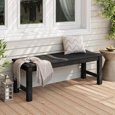 a black bench sitting on top of a wooden floor next to a white wall and window