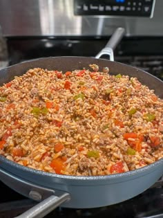 a pan filled with rice and vegetables on top of a stove next to an oven