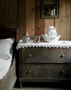 an old dresser with a white bowl on top and a clock sitting on it's side