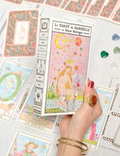 a person holding up a tarot and mashede card in front of many other cards