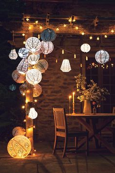 an outdoor dining area with lights strung from the ceiling and hanging lanterns on the wall