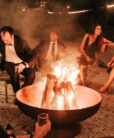 people sitting around a fire pit with drinks