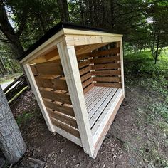 a wooden outhouse in the woods with wood slats on the floor and roof