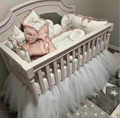 a baby crib with white and pink bedding on top of carpeted floor