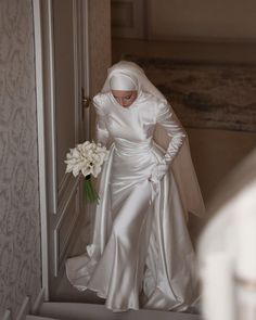 a woman in a white wedding dress is walking down the stairs