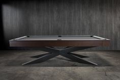 a pool table with an x - base in the middle and dark wood walls behind it