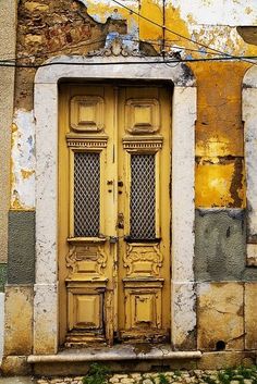 an old yellow door in front of a crumbling building