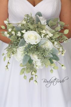 a bride holding a bouquet of white flowers and greenery