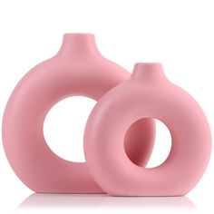 two pink vases sitting next to each other on a white surface, one is shaped like an ovoid