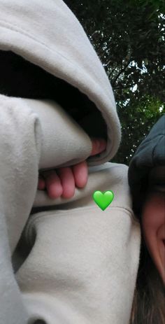 a woman wearing a hoodie with a green heart sticker on it's chest