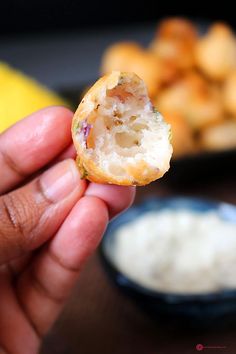 a person holding up a half eaten doughnut in front of some dipping sauces