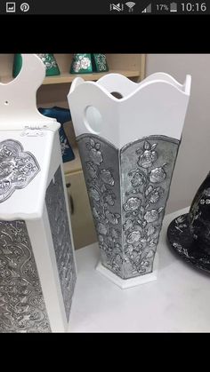 two white vases sitting on top of a table next to each other in front of boxes