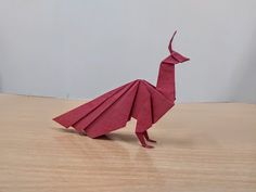 a red origami bird sitting on top of a wooden table