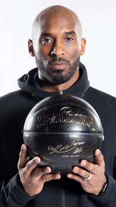 a man holding a basketball in front of his face while wearing a black hoodie